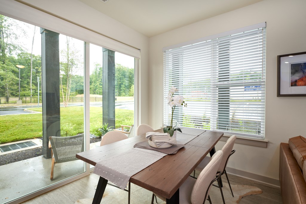 A dining room with a table and chairs and a view of the outside.