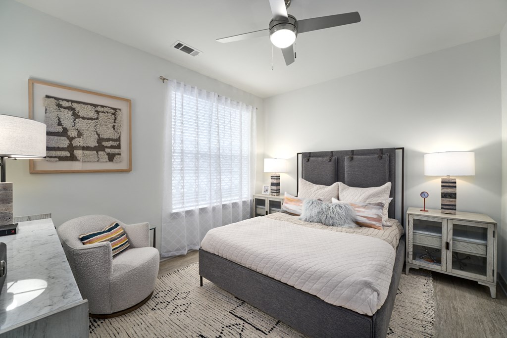 A bedroom with a large bed, a chair, and a ceiling fan.