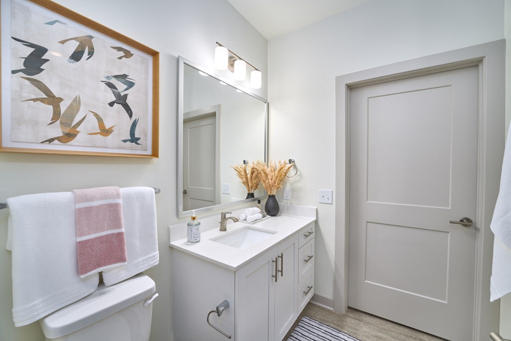 A white bathroom with a towel hanging on the toilet.