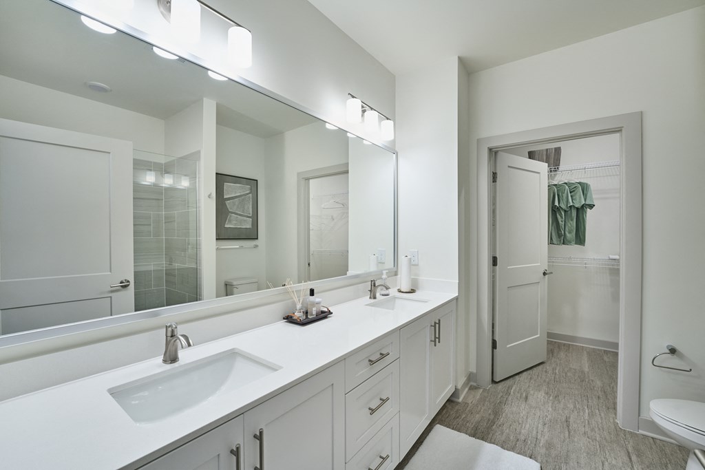 A white bathroom with a sink, mirror, and toilet.
