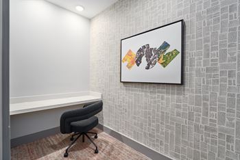 A framed artwork hangs on a wall above a black office chair.
