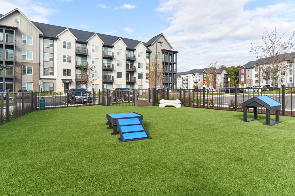 A park area with a blue slide in front of apartment buildings.