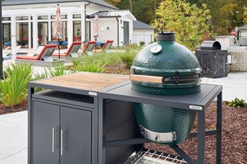 A green grill is on a table outside.