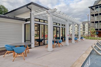 A patio with a table and chairs is covered by a white pergola.