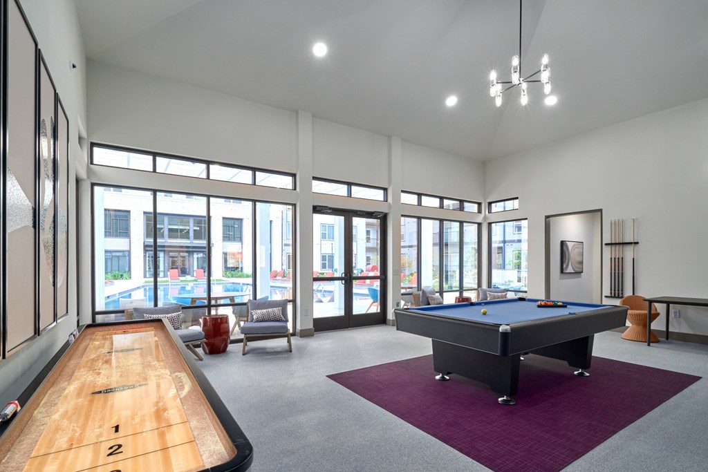 A billiard table is in the middle of a room with a pool table and a foosball table.