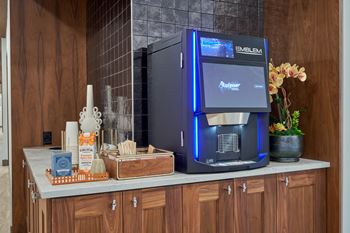 A modern kitchen with a coffee machine and a wooden cabinet.