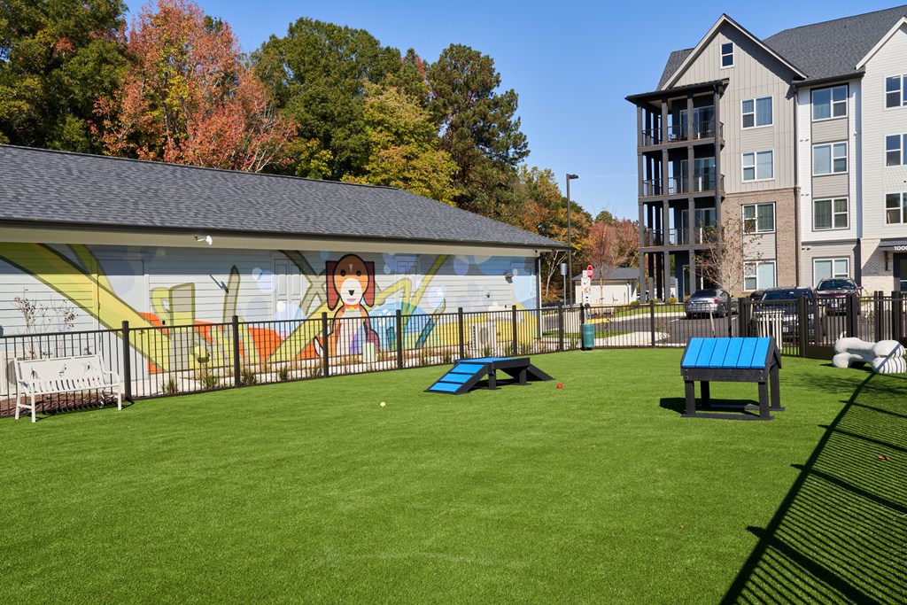 A park with a mural on a wall and a blue bench.