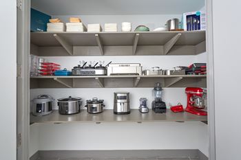A kitchen pantry with a red mixer on the bottom shelf.