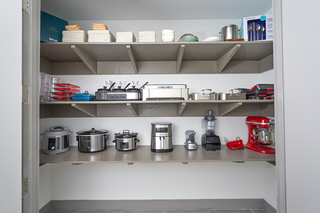 A kitchen pantry with a red mixer on the bottom shelf.
