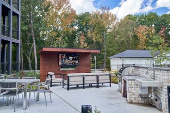 A patio with a couch, chairs, and a TV.