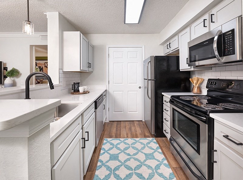 A kitchen with black appliances and white cabinets.