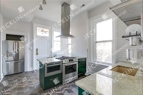 A kitchen with a green island and stainless steel appliances.