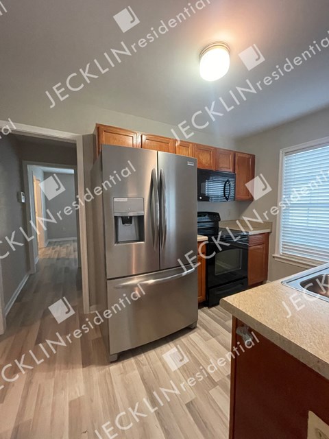 A modern kitchen with a stainless steel refrigerator and wooden cabinets.