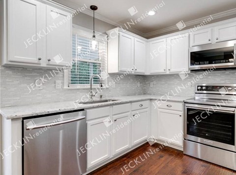 A modern kitchen with white cabinets and stainless steel appliances.