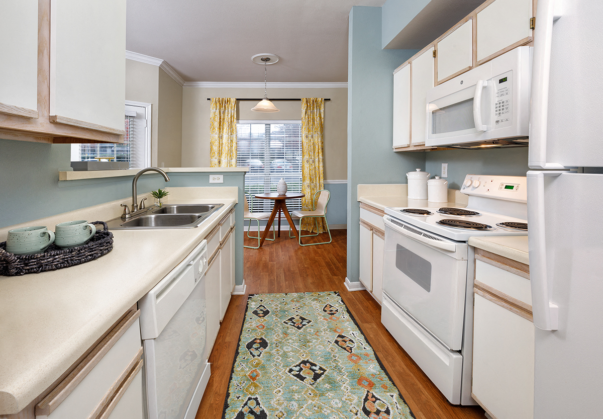 a kitchen with white appliances and a rug