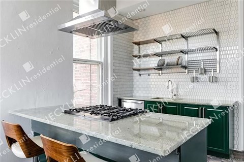 A modern kitchen with a large island and a stove top.