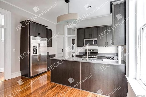 A modern kitchen with dark wood cabinets and stainless steel appliances.