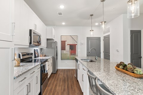 A kitchen with white cabinets and a marble countertop.