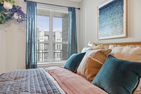 A bedroom with a large bed and a window with curtains.
