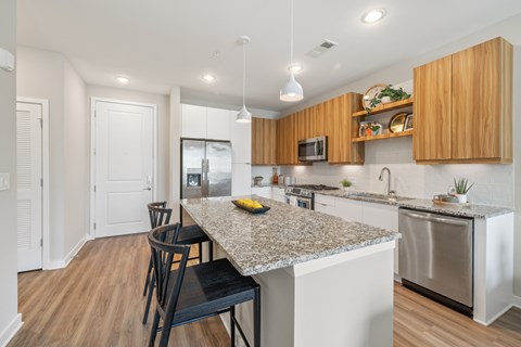 A kitchen with a granite countertop and wooden cabinets.