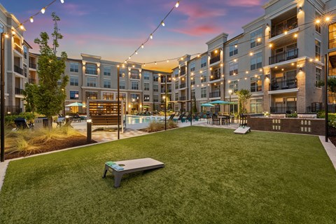 A sunset view of a grassy area with a bench and apartment buildings in the background.