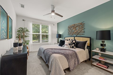 A bedroom with a bed, a ceiling fan, and a window.