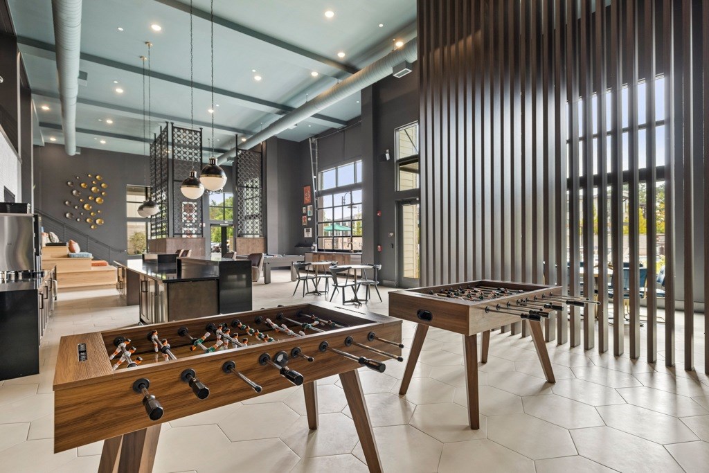 A foosball table is in the middle of a room with a bar and a dining table.