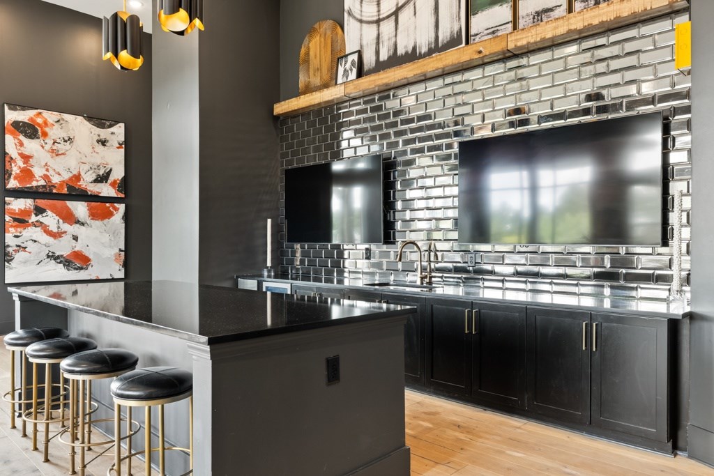 A modern kitchen with a black countertop and gold bar stools.