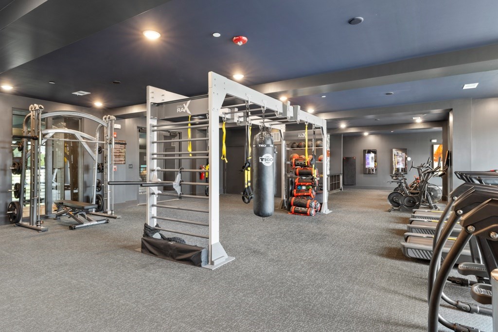 A gym with a variety of equipment including treadmills, weights, and exercise machines.