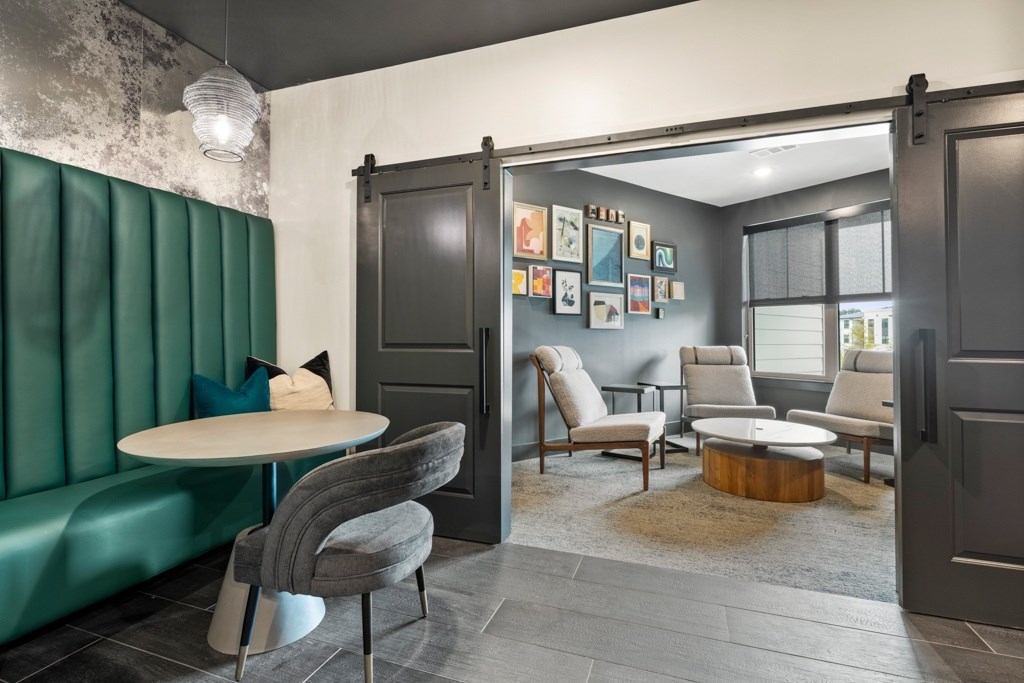 A room with a green sofa, grey chairs, a white table, and pictures on the wall.