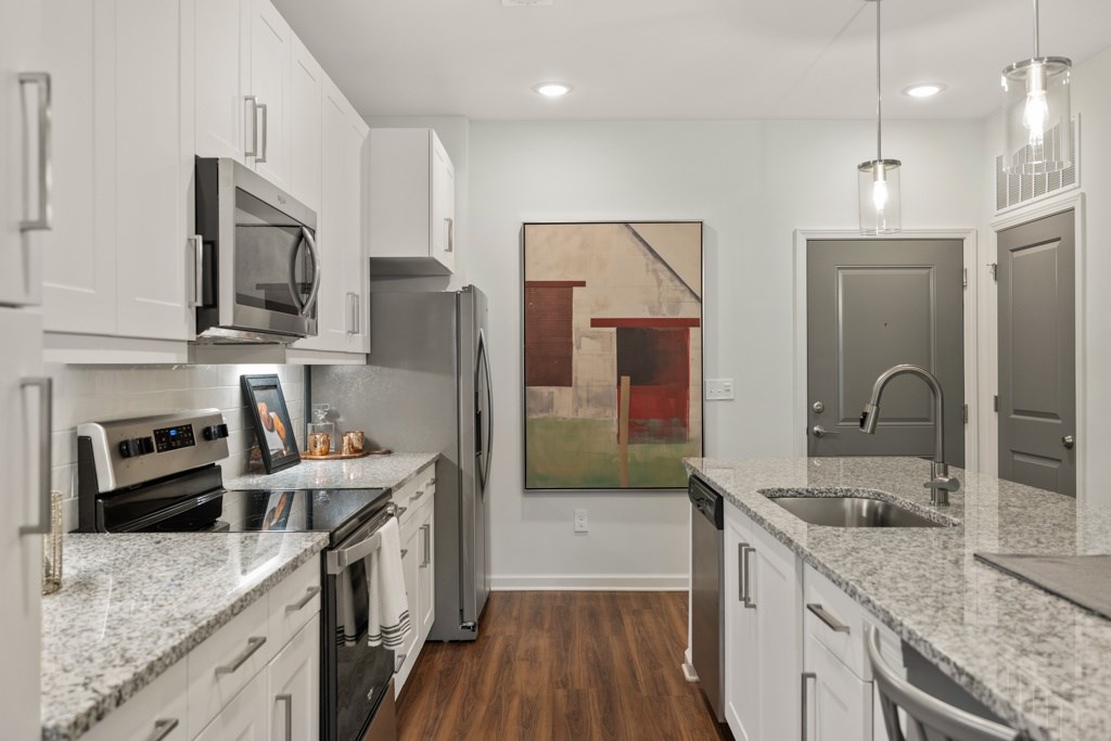 A kitchen with white cabinets and a painting hanging on the wall.