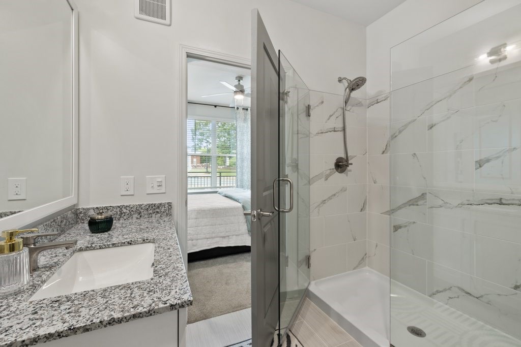 A bathroom with a marble countertop and a walk-in shower.