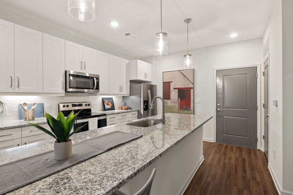 A kitchen with granite countertops and a grey door.