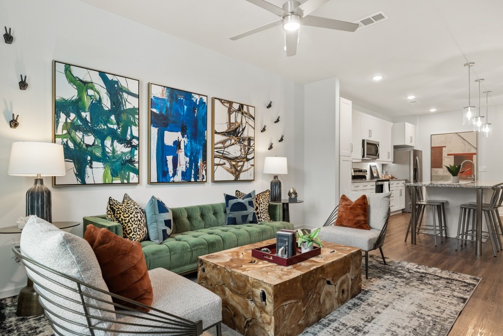 A living room with a green couch, a coffee table, and a painting on the wall.