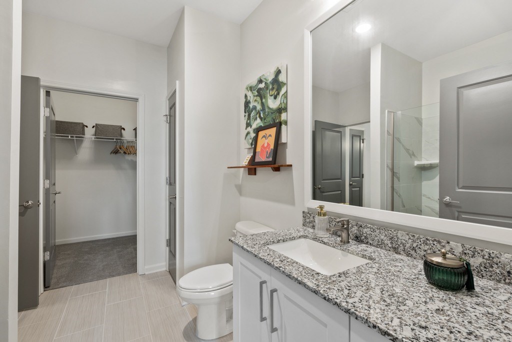 A bathroom with a toilet, sink, and mirror.