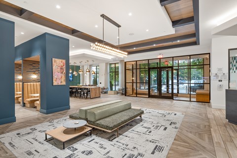 A spacious lobby with a patterned rug and a green sofa.