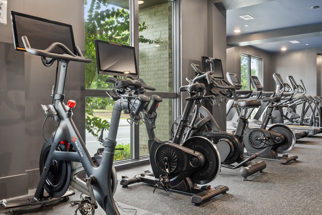 A gym with a row of stationary bikes.