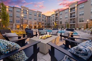 a patio with a fire pit and a pool in front of an apartment building