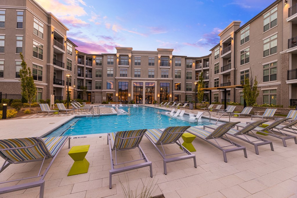 a swimming pool with chaise lounge chairs and a building in the background