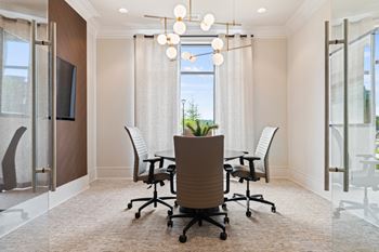 A conference room with a table, chairs, and a plant.