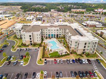 an aerial view of a large apartment complex with a pool in the middle of the parking lot