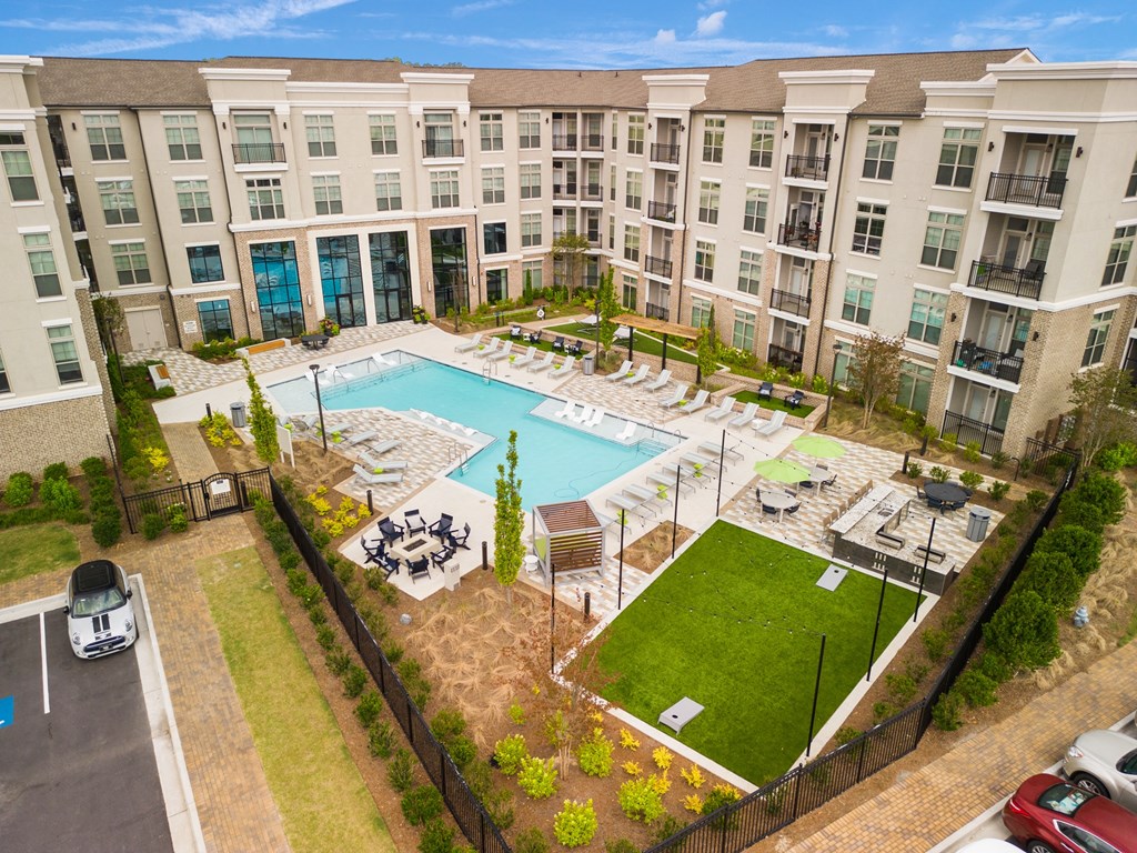 an aerial view of the resort style pool with chaise lounge chairs and grassy area