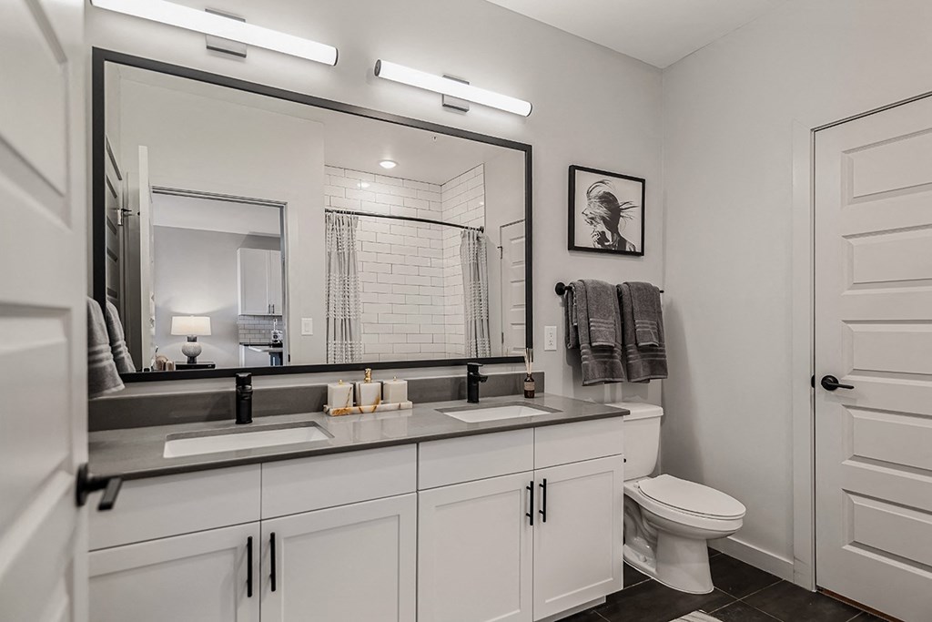 A white bathroom with a toilet, sink, and mirror.