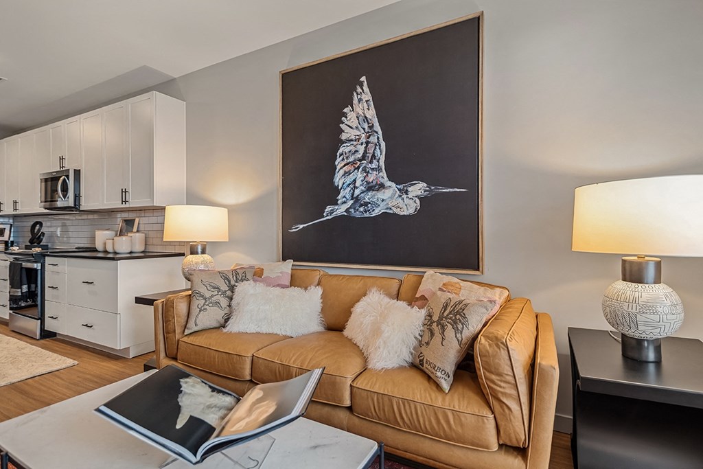 A living room with a couch, a coffee table, and a painting of a bird on the wall.