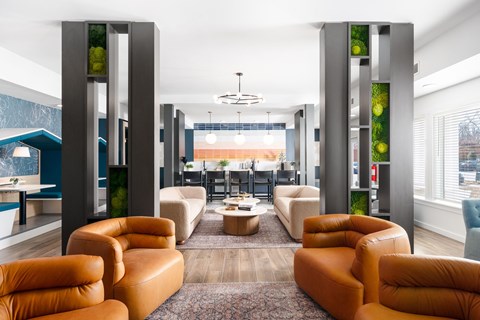 A modern living room with orange leather chairs and a glass table.