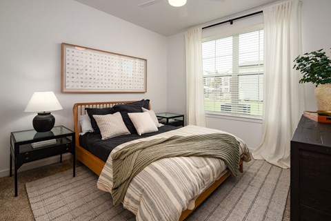 a bedroom with a bed and a window with white curtains