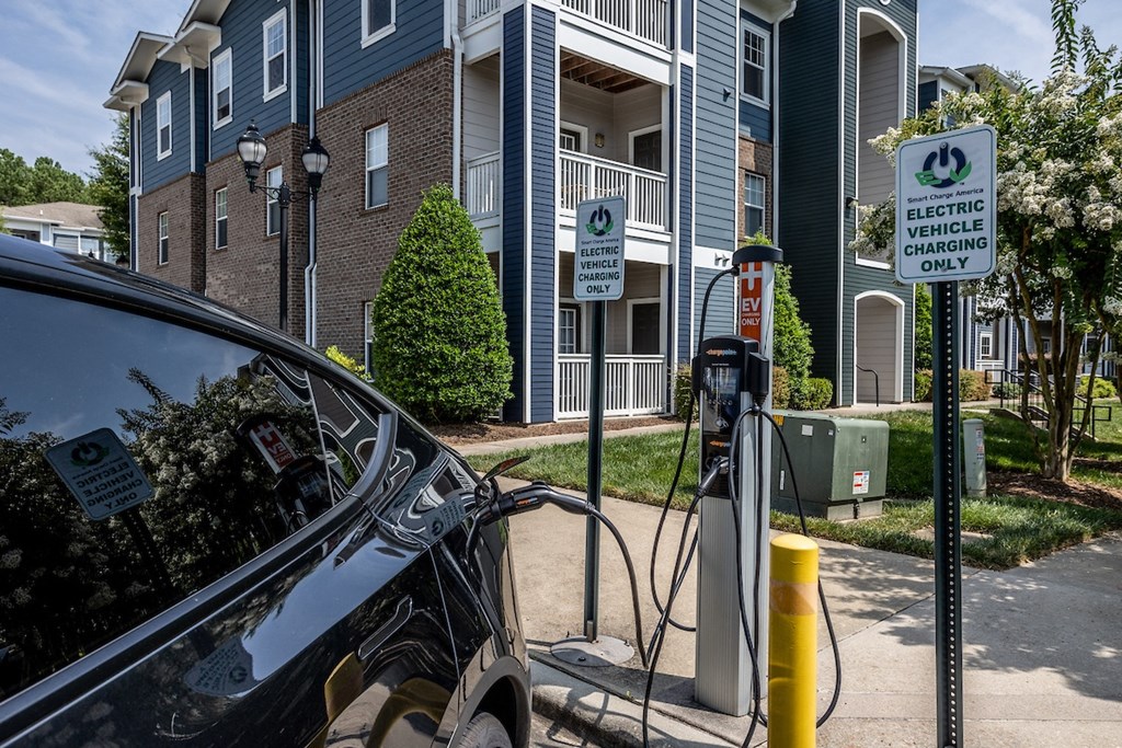 a car is plugged into a charging station in front of an apartment building