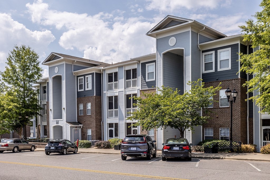 a large apartment complex with cars parked in front of it