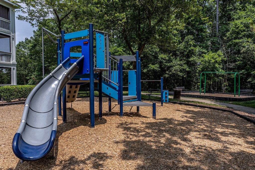 a blue playground with a slide in the middle of a park