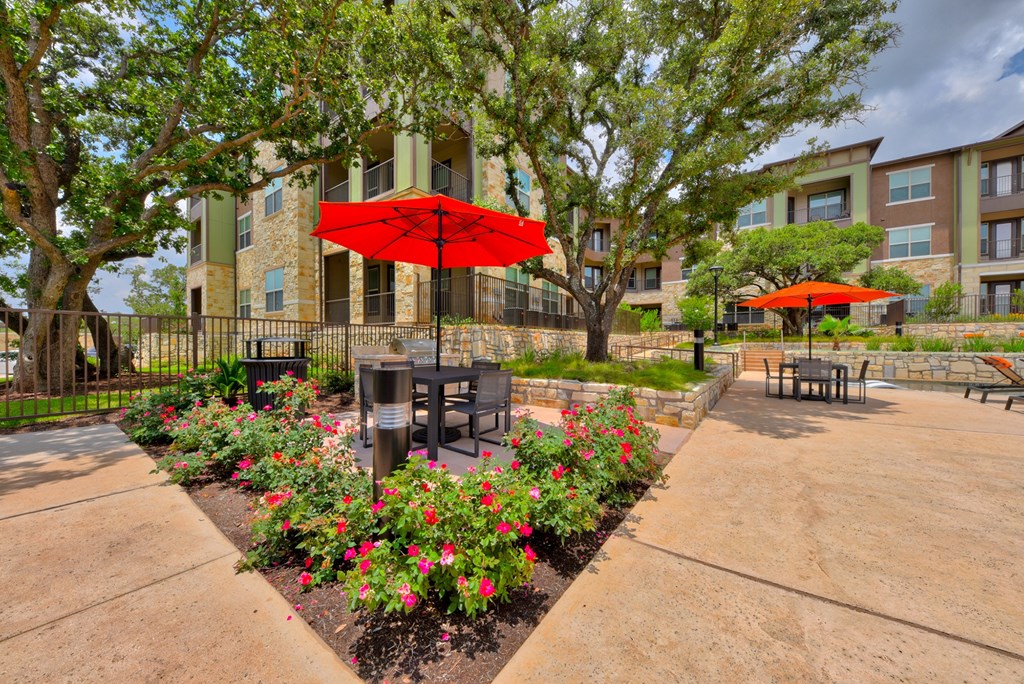 a courtyard with tables and umbrellas in front of an apartment building